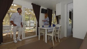 Una habitación con comedor, televisión y puerta corrediza de vidrio que da a una terraza exterior.