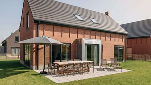A modern house with a brick exterior, a sloped roof, and a patio with a table and chairs. - Villa by Lake Veere With Sauna (Wolphaartsdijk)