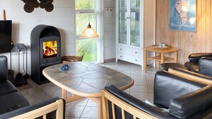 A cozy living room with a fireplace, a dining table, and comfortable seating. - 6 Person Holiday Home in Thisted (Thisted)