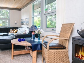 A cozy living room with a sofa, a wicker chair, a small table, and a fireplace. - 6 Person Holiday Home in Skovgårde Allingåbro (Allingåbro)