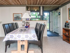 A dining area with a table set for six, surrounded by chairs, and a kitchen visible in the background. - 6 Person Holiday Home in Skovgårde Allingåbro (Allingåbro)
