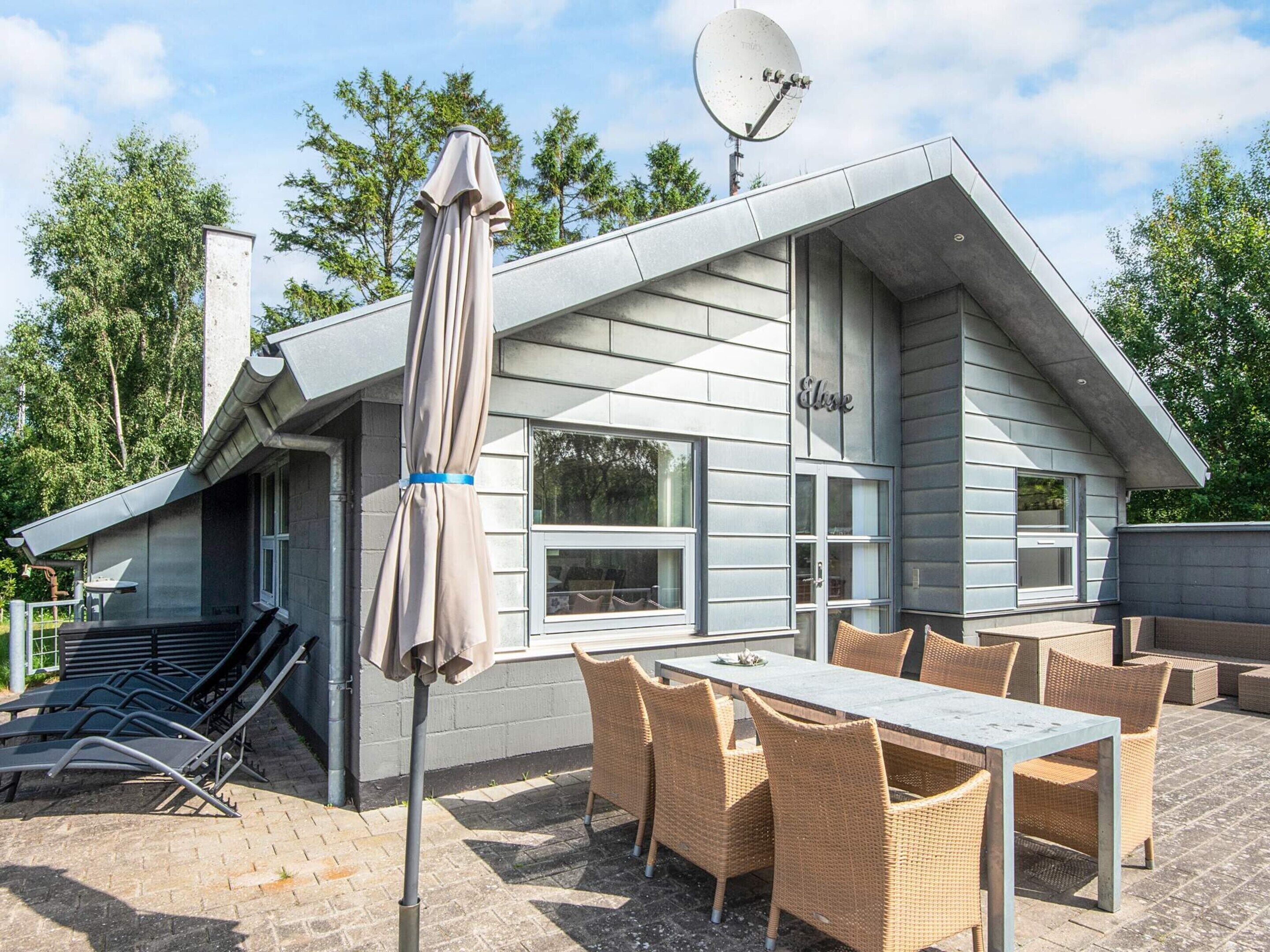 A modern house with a patio area featuring outdoor furniture and a satellite dish.