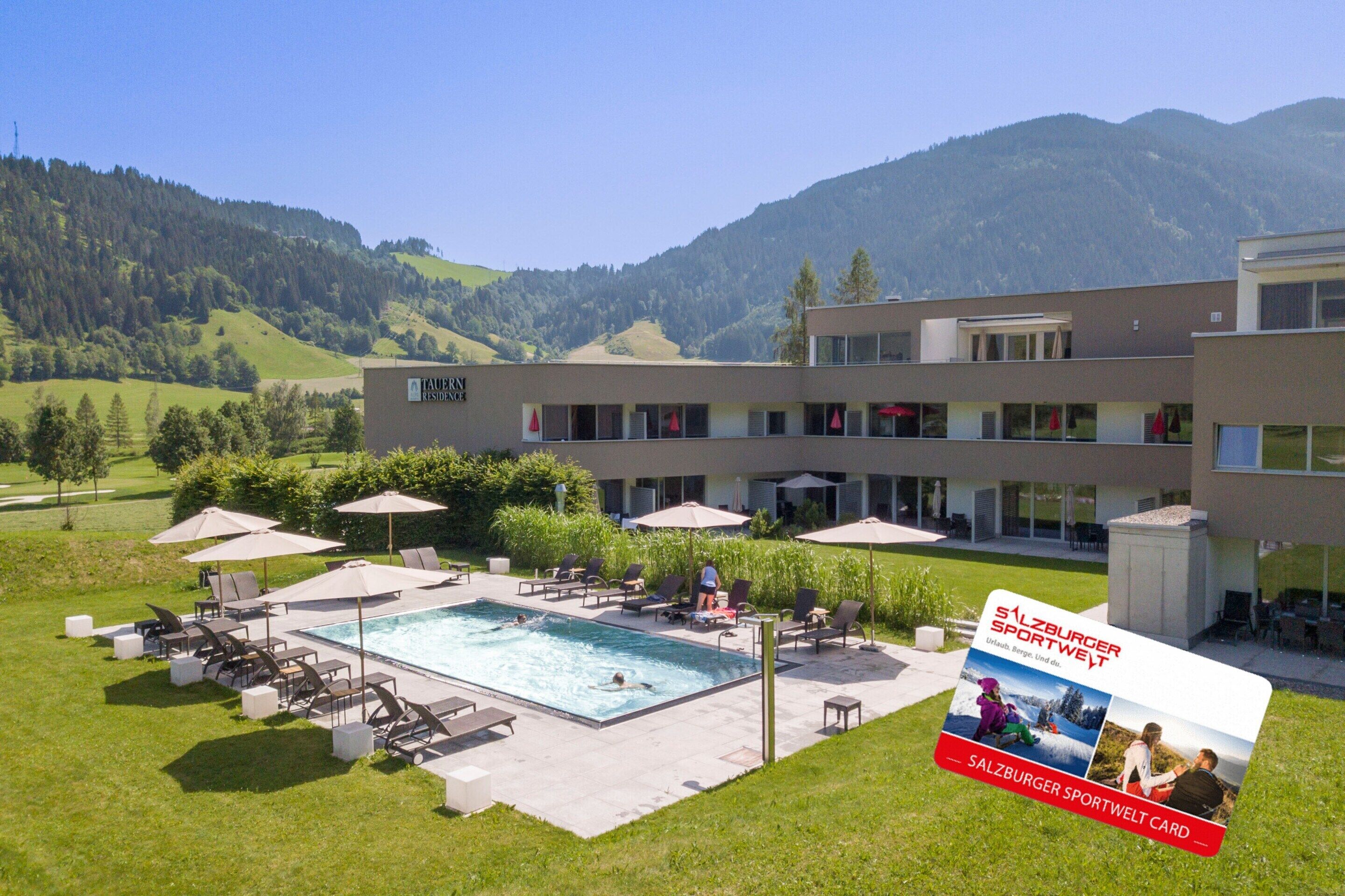 A hotel with a swimming pool, outdoor seating, and a view of mountains.