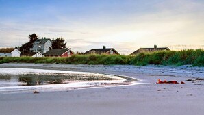 Een strand met huizen op de achtergrond en een zandstrand.