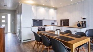 Een moderne keuken met witte kasten, een houten eettafel en zwarte stoelen.