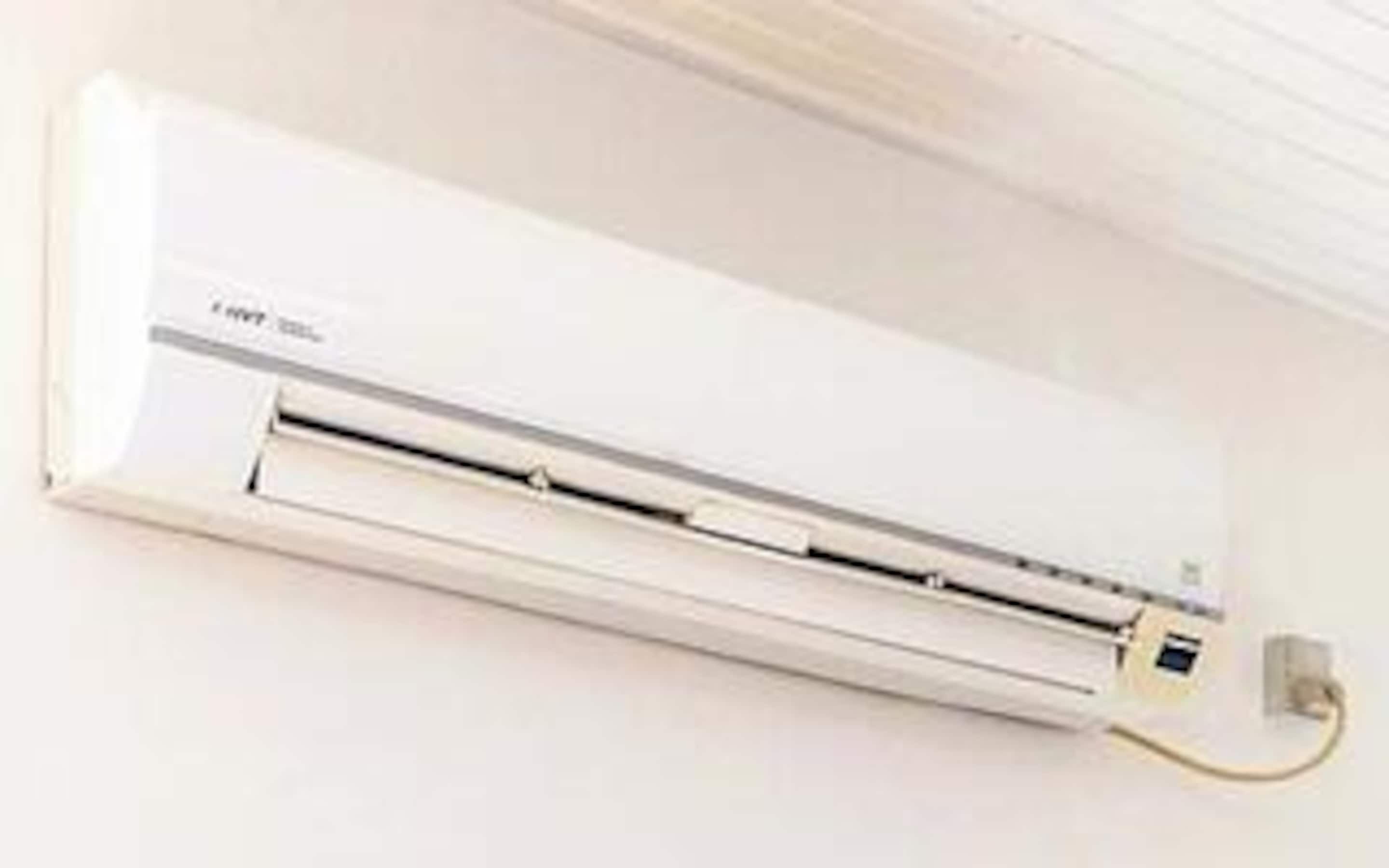 A wall-mounted air conditioner with a control panel and a power cord.