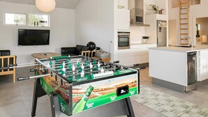 A modern living room with a foosball table, a flat-screen TV, and a comfortable seating area. - Holiday Home in Jerup (Jerup)