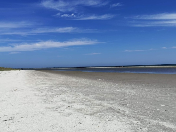 En bred sandstrand med klar himmel.