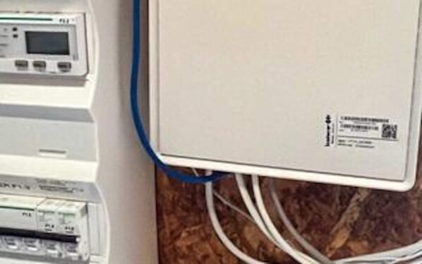 Et kontrolpanel med et digitalt display og flere knapper, tilsluttet en hvid enhed med en etiket.