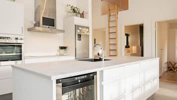 Cozinha moderna com lava-louças, eletrodomésticos de aço inoxidável e uma ilha central.