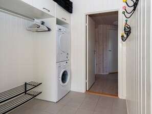 A laundry room with a front-loading washer and dryer, a drying rack, and a door leading to another room. - Holiday Home in Nørre Nebel (Norre Nebel)