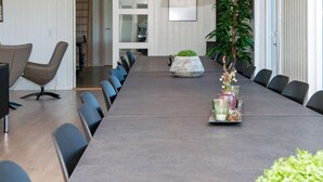 A conference room with a long table, chairs, pendant lights, a potted plant, and a decorative vase. - Holiday Home in Nørre Nebel (Norre Nebel)