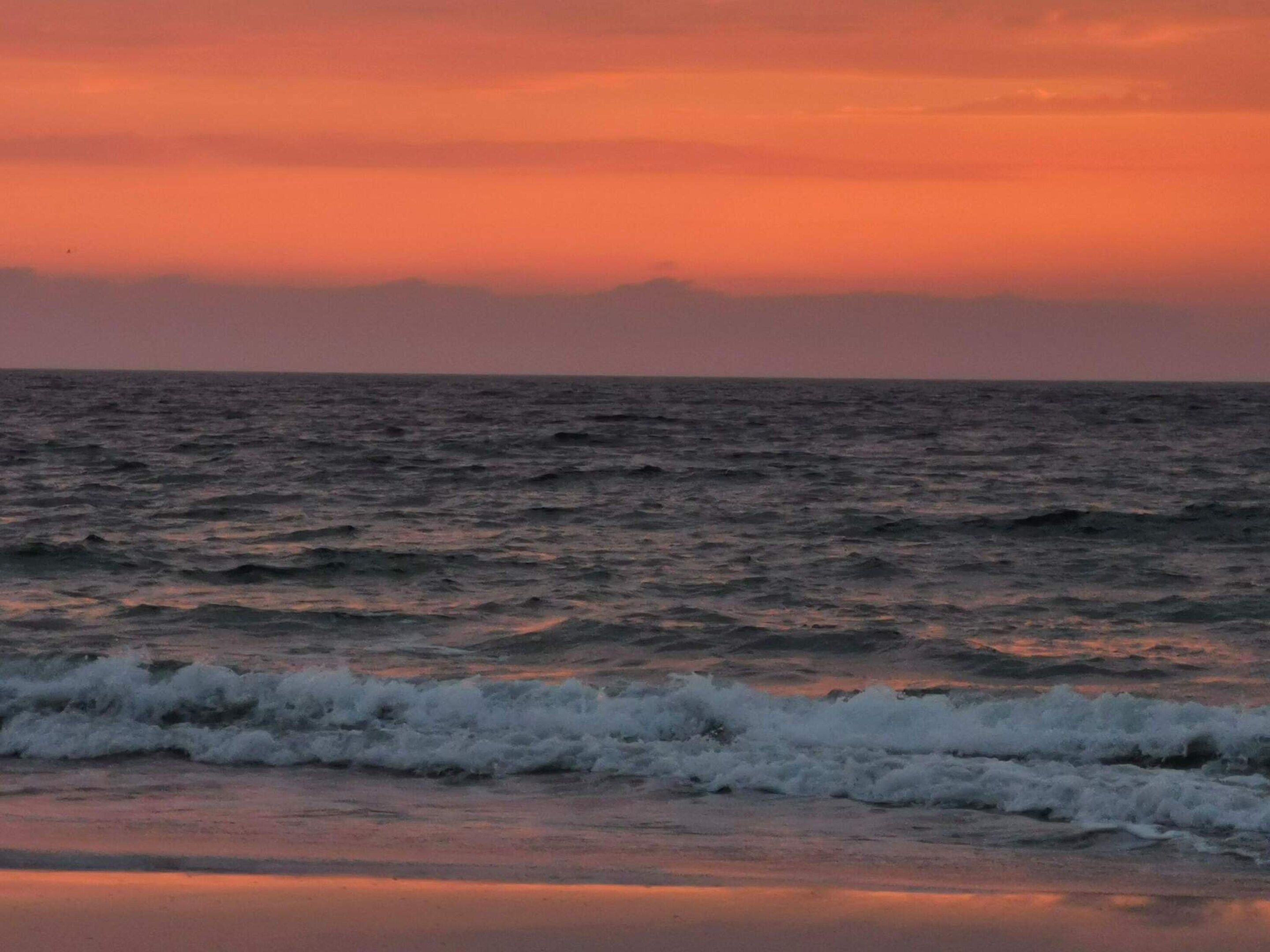 A beach with waves at sunset.