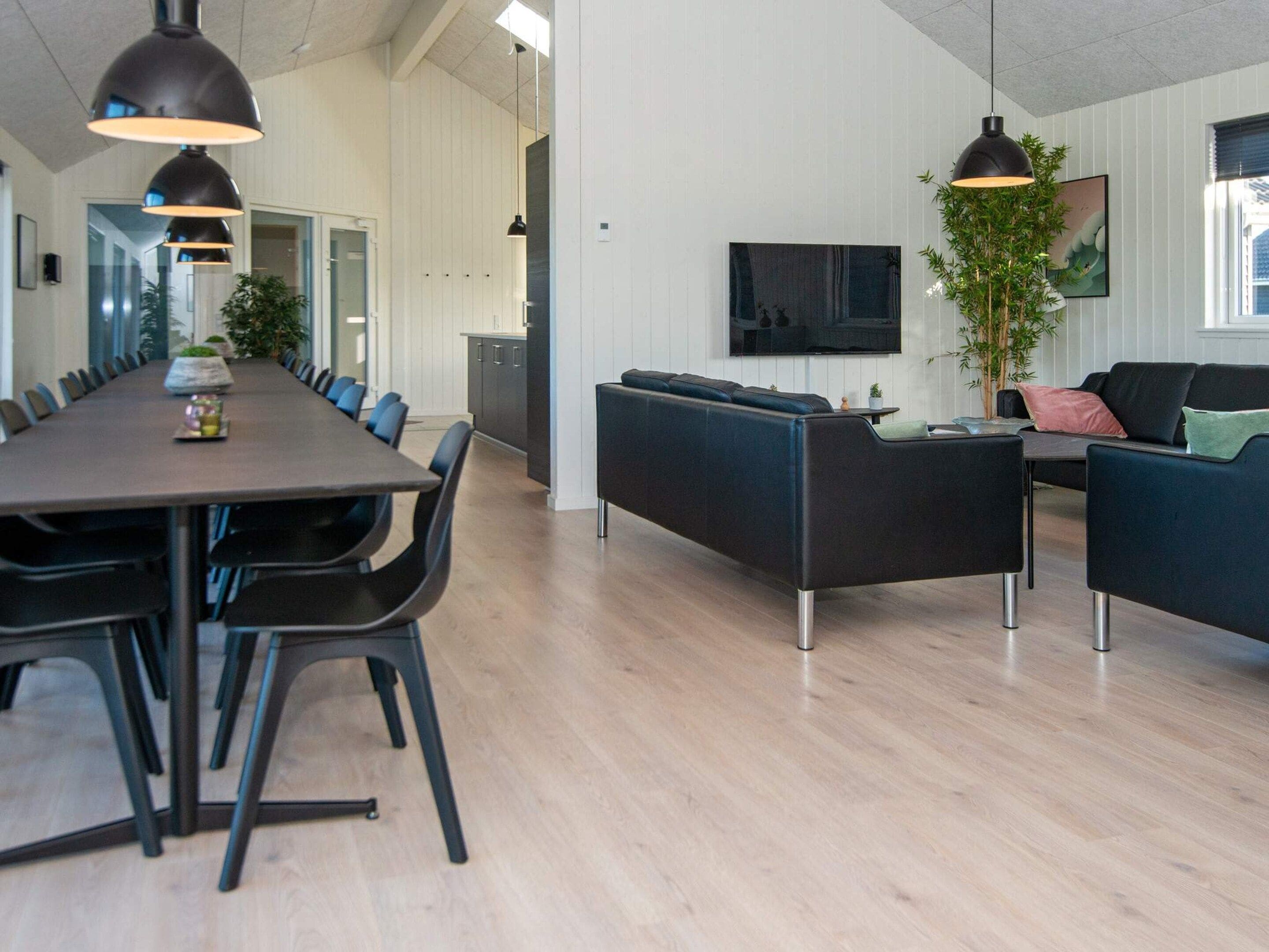 Et moderne interiør med spiseplads, sofaer og et fjernsyn.