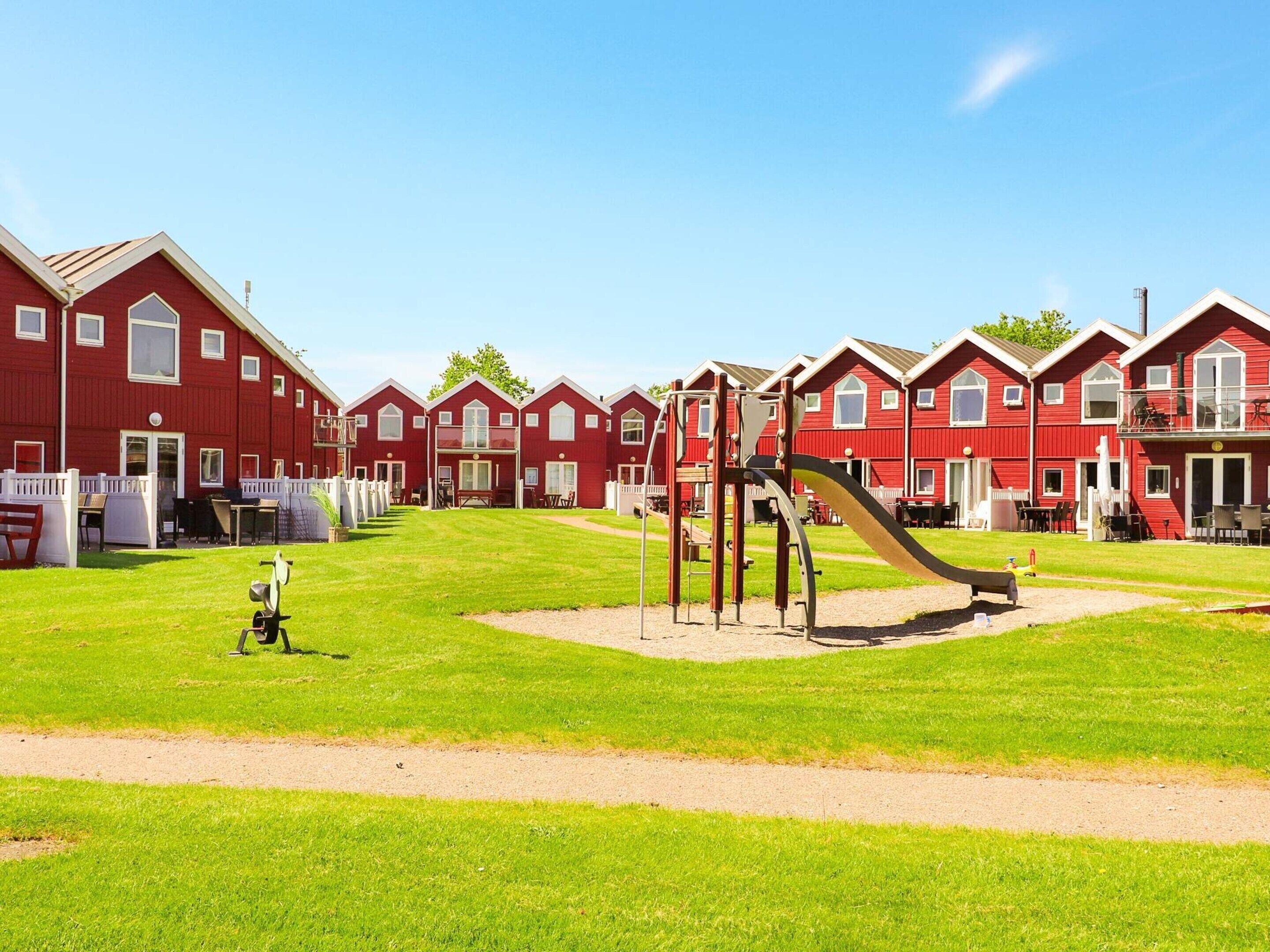 A row of red houses with a playground in the middle.