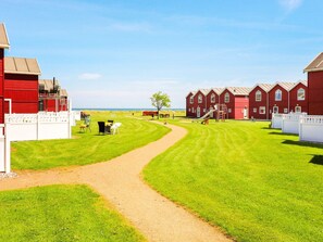 A red barn and a row of red houses with a clear path leading to a grassy area.