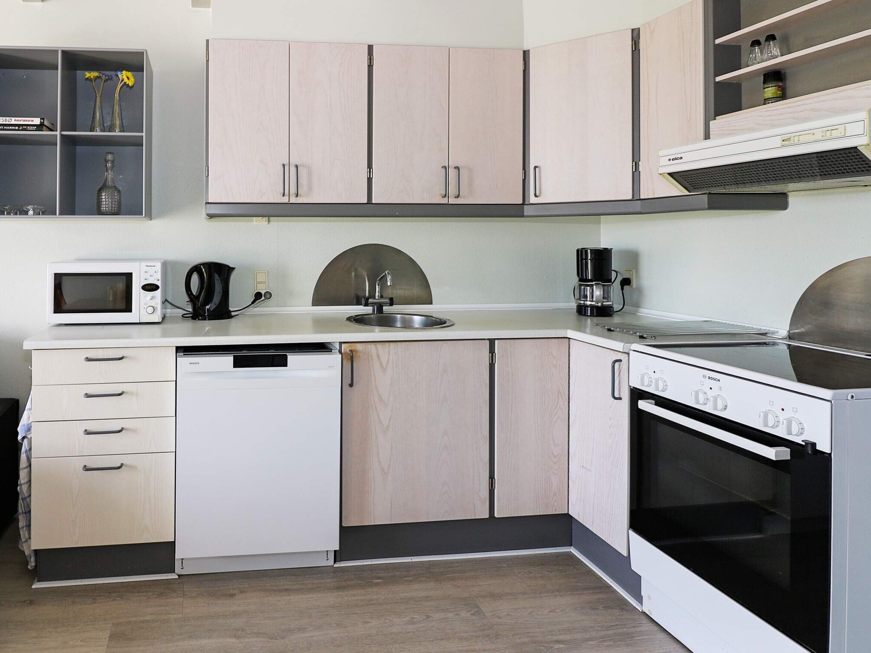 A compact kitchen with a microwave, coffee maker, sink, dishwasher, and stove.