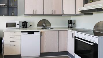 A compact kitchen with a microwave, coffee maker, sink, dishwasher, and stove.