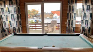 A pool table with a view of a harbor and boats, wooden walls, and curtains with a nautical theme. - 6 Person Holiday Home in Bomlo (Bomlo)
