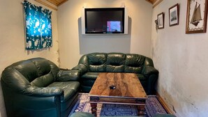 A cozy room with a green leather sofa, a wooden coffee table, and a flat-screen TV mounted on the wall. - 6 Person Holiday Home in Bomlo (Bomlo)