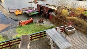 A wooden deck with outdoor furniture, a small garden, and a dock with boats. - 6 Person Holiday Home in Bomlo (Bomlo)