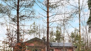 Een roze huis omgeven door hoge bomen.