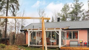 Een huis met een overdekte patio, een schommel en uitzicht op het omliggende bos.