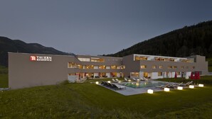 Un hotel moderno con piscina, area salotto all'aperto e montagne sullo sfondo.