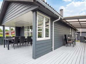 A covered patio with outdoor furniture, a large window, and a chimney.