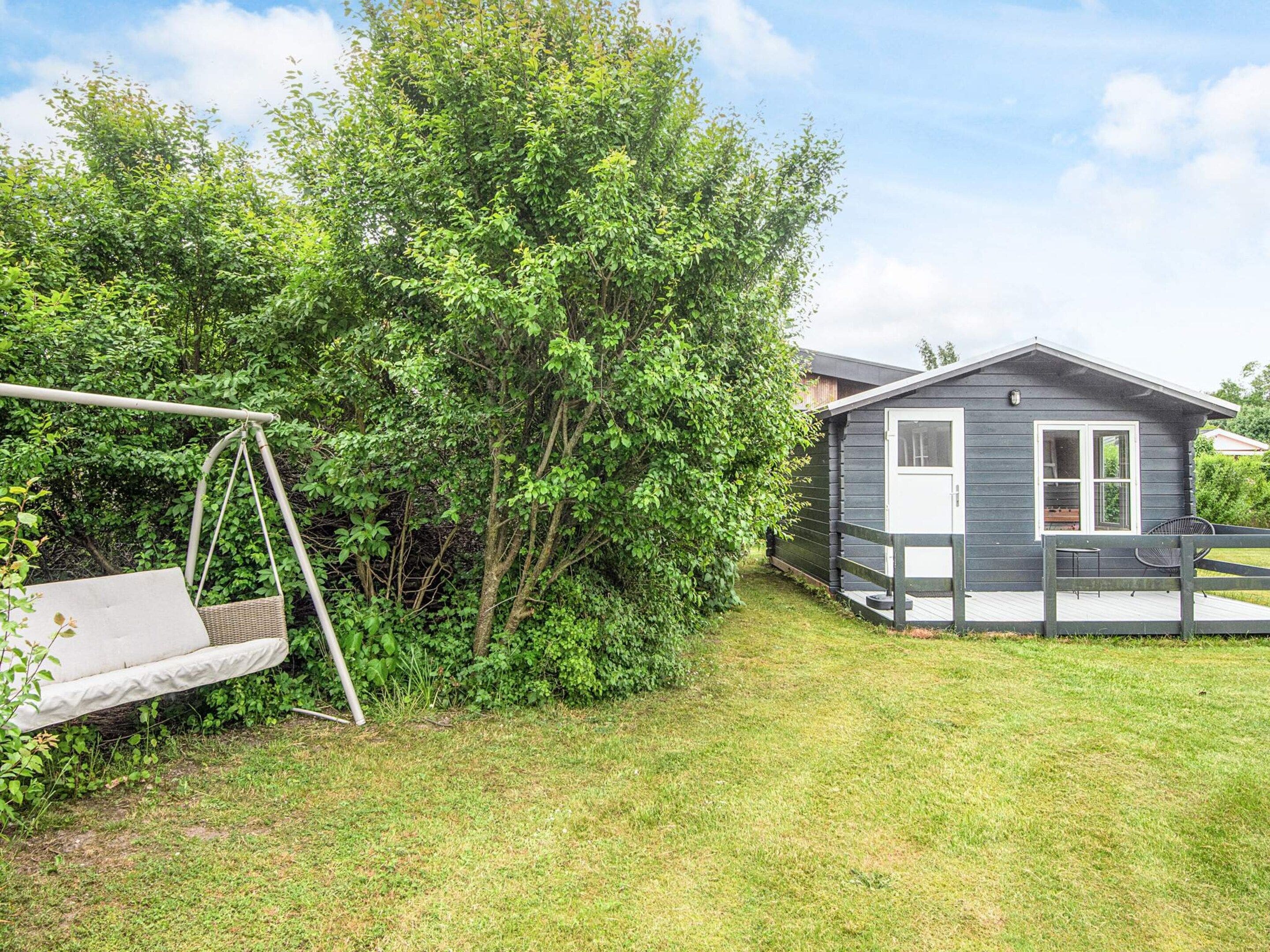 A small cabin with a deck, surrounded by lush greenery.