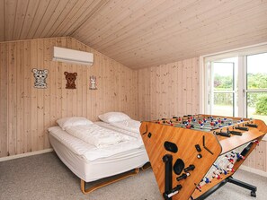 Una habitación con una cama, mesa de fútbol y paredes de madera.