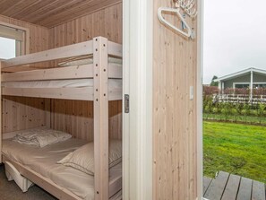 Simple, functional room with a wooden ceiling and walls, featuring a single bunk bed and a small window.