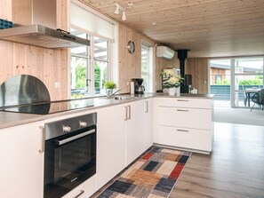 A modern kitchen with wooden cabinetry, a Bosch oven, a coffee maker, and a view to the outside. - Holiday Home in Haderslev (Haderslev)