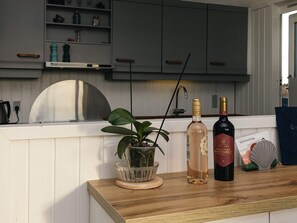 A kitchen counter with two bottles of wine, a potted plant, and a decorative item.