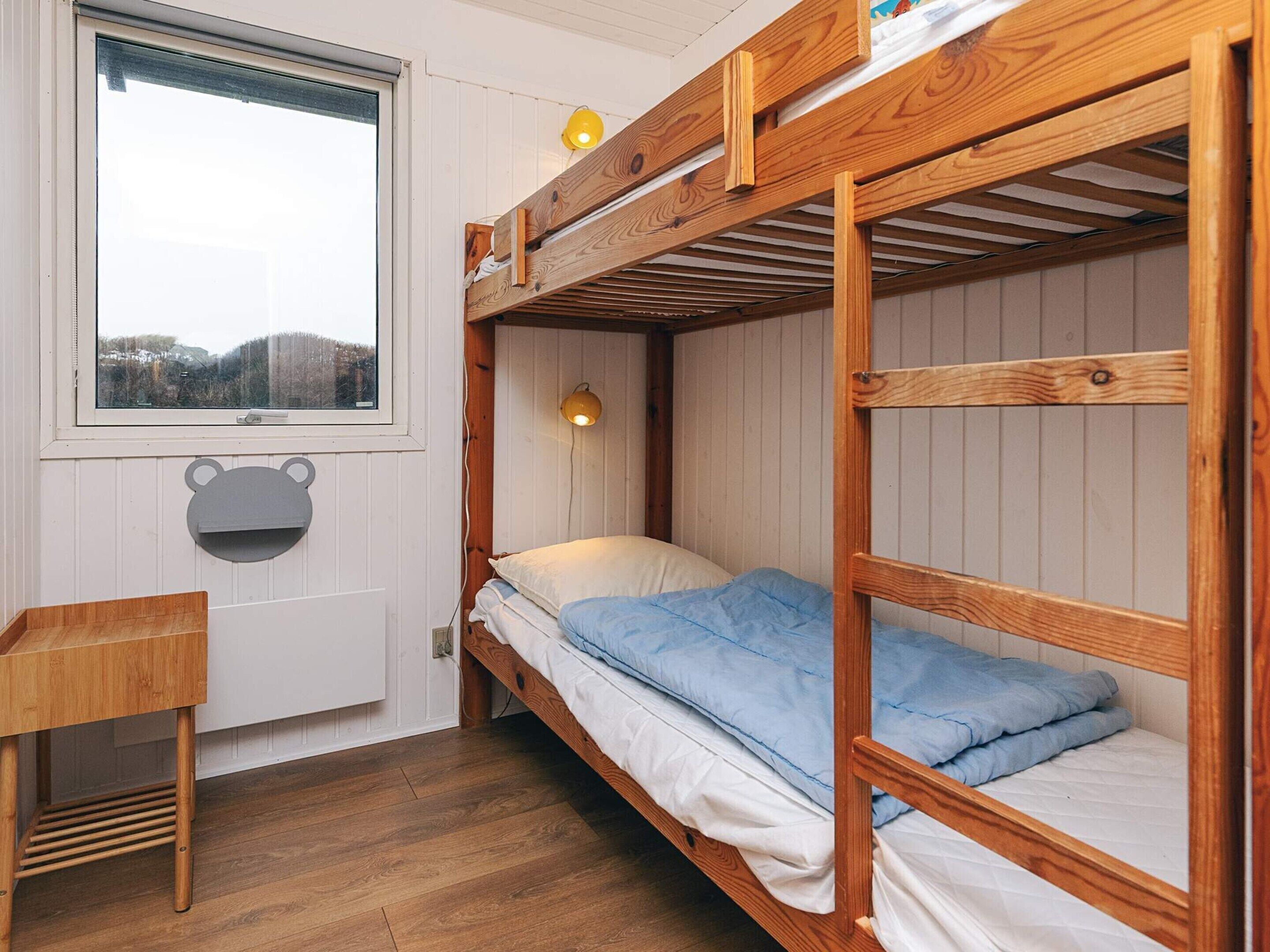A bunk bed room with a window, a desk, and a bear-shaped decoration.