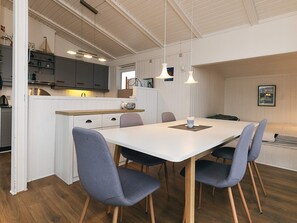 A modern kitchen with white cabinets, a wooden countertop, and pendant lighting.