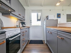 A modern kitchen with grey cabinets, wooden countertops, a Bosch stove, and a refrigerator.