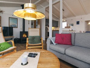 A cozy living room with a fireplace, a sofa, a chair, and a television.