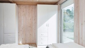 A bedroom with a wooden ceiling, a large wardrobe, a bed, and a sliding glass door to the outside. - 8 Person Holiday Home in Borkop (Borkop)