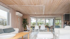 A modern living room with a wooden ceiling, white furniture, and a large window. - 8 Person Holiday Home in Borkop (Borkop)