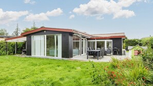 A modern house with a patio, large sliding glass doors, and a well-maintained lawn. - 8 Person Holiday Home in Borkop (Borkop)