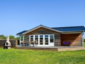 Relax in a cozy cabin-style building with a covered patio, large windows, and a fire pit.