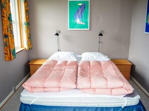 A bedroom with a bed, two bedside tables, a window with curtains, and a wall-mounted picture. - 6 Person Holiday Home in Lokken (Lokken)