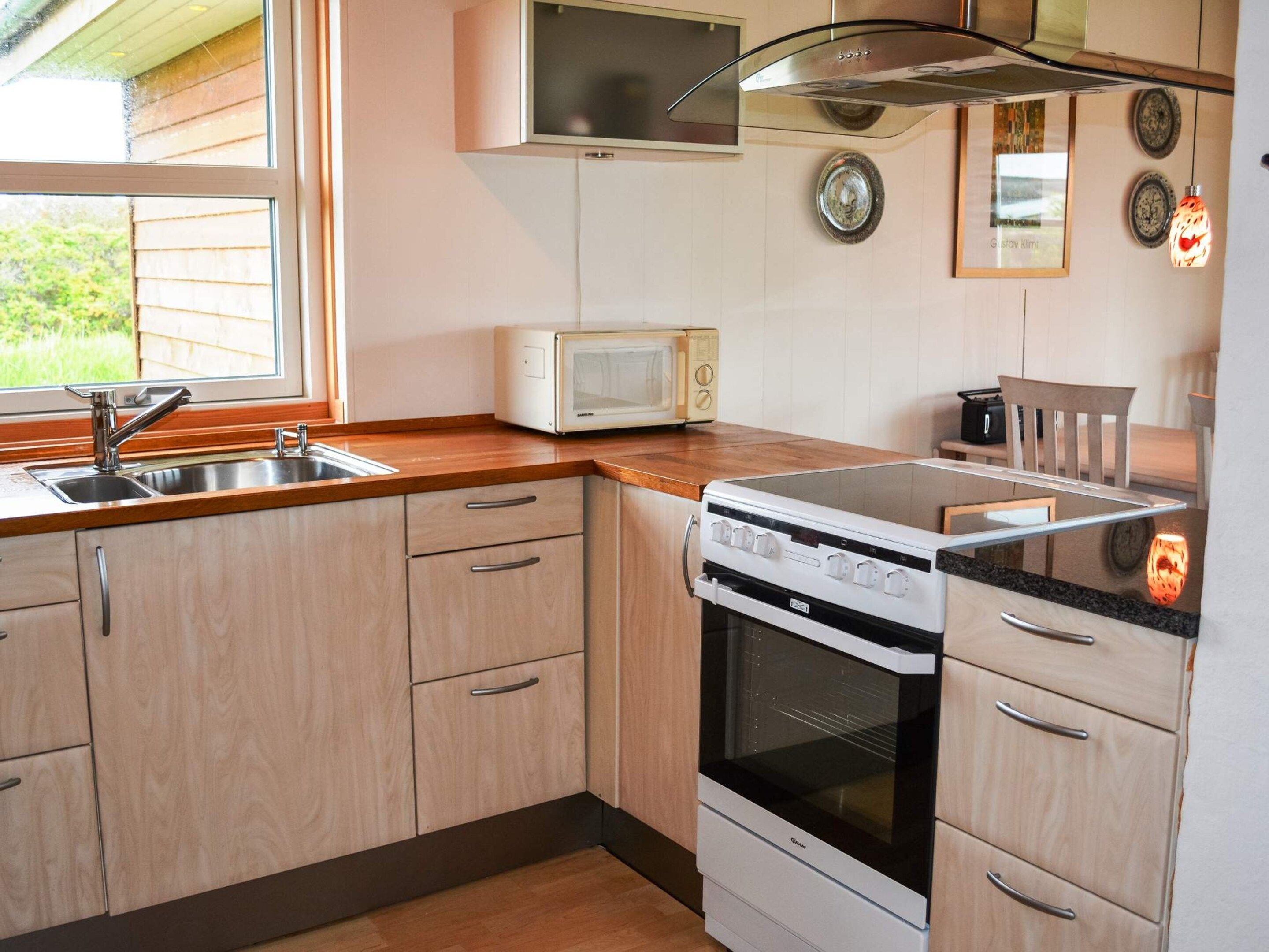 Een kleine keuken met een ingebouwde magnetron, fornuis en spoelbak.