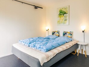 A bedroom with a bed, two wall-mounted lamps, and a painting on the wall. - Holiday Home in Hals (Hals)