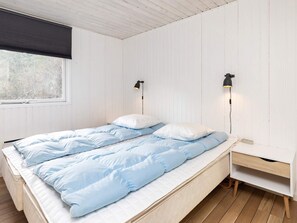 A bedroom with a bed, two bedside lamps, a window, and a nightstand. - 6 Person Holiday Home in Blokhus (Blokhus)