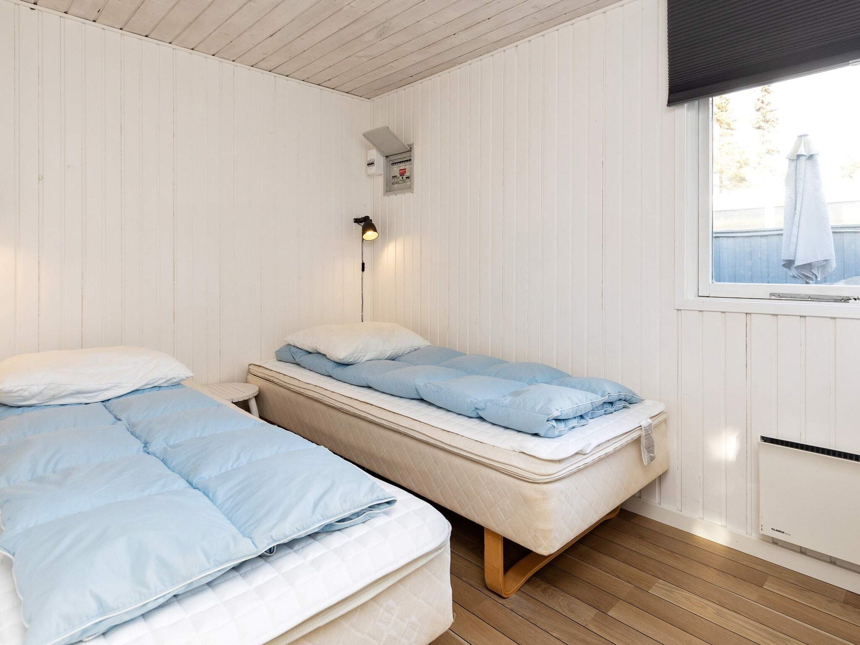 A room with two beds, a window with a view, and a wall-mounted heater.