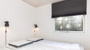 A single bed with white bedding, two wall-mounted lamps, and a window with a dark blind. - 6 Person Holiday Home in Blokhus (Blokhus)