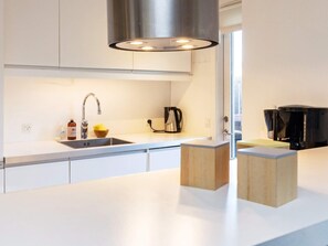 A modern kitchen with a stainless steel sink, a kettle, and a coffee maker. - 6 Person Holiday Home in Blokhus (Blokhus)