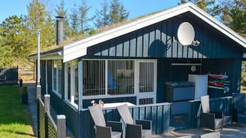 A small, single-story building with a covered patio area, a satellite dish, and outdoor seating.